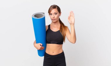 Güzel bir kadın ciddi görünüyor. Avuç içi gösteriyor. Durma hareketi yapıyor. yoga konsepti