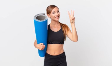 Güzel bayan gülümsüyor ve arkadaş canlısı görünüyor, üç numarayı gösteriyor. yoga konsepti