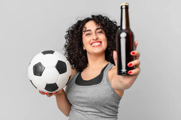 pretty arab woman with a soccer ball and having a beer