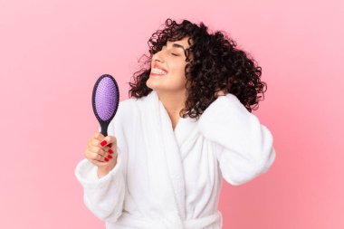 Bornoz giyen ve elinde saç fırçası tutan güzel bir Arap kadın.