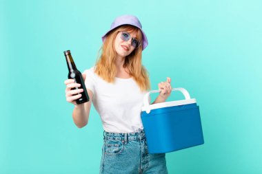 Portatif buzdolabı ve birası olan güzel kızıl saçlı kadın.