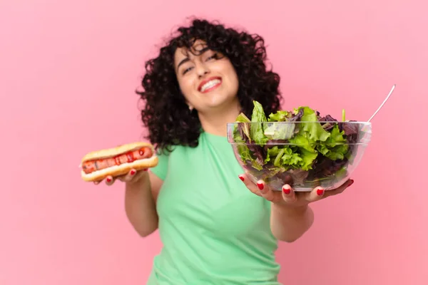 サラダとホットドッグを持った可愛いアラブ人女性 食事のコンセプト — ストック写真