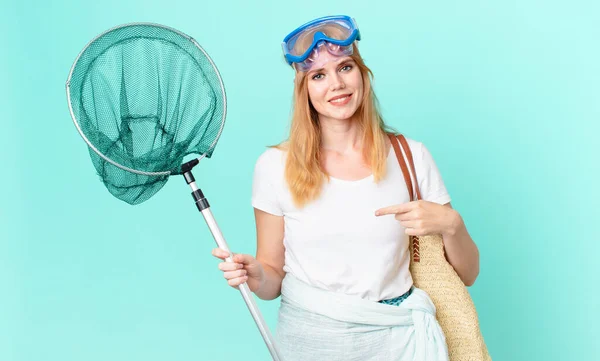 pretty red head woman with a fisher net and goggles.