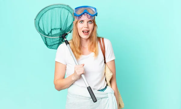 pretty red head woman with a fisher net and goggles.