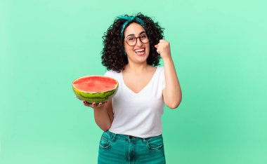 Güzel Arap kadın şoke olmuş, gülüyor, başarıyı kutluyor ve elinde bir karpuz tutuyor. yaz konsepti