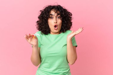 Güzel Arap kadın şaşırmış ve şok olmuş görünüyor, çenesi düşmüş, elinde bir nesneyle. sigara içilmiyor