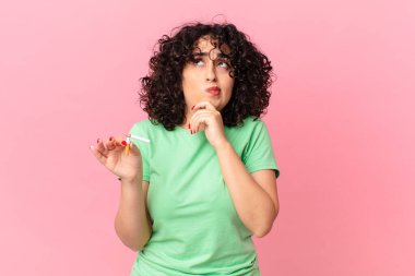 Güzel Arap kadın düşünüyor, kuşkulu ve şaşkın hissediyor. sigara içilmiyor