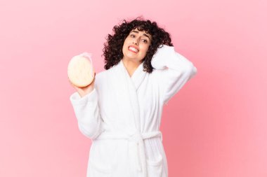 Güzel Arap kadın kendini stresli, endişeli ya da korkmuş hissediyor. Elleri kafasında bornoz ve sünger tutuyor.