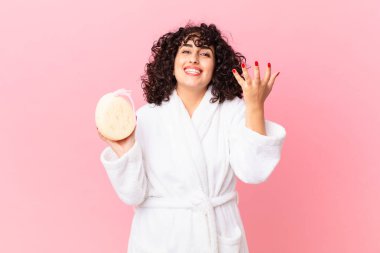 Güzel Arap kadın kendini mutlu hissediyor, bir çözüm ya da fikir bulduğunda bornoz giyiyor ve sünger tutuyor.