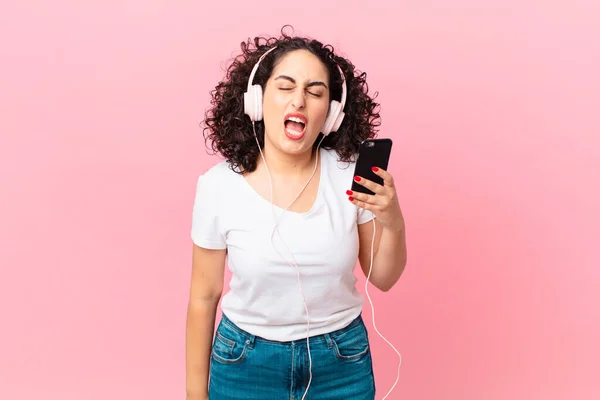 Гарна Арабська Жінка Кричить Агресивно Виглядає Дуже Сердито Навушниками Смартфоном — стокове фото