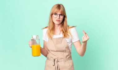 Güzel kızıl saçlı kadın kızgın, sinirli, asi ve agresif bir şekilde portakal suyu hazırlıyor.