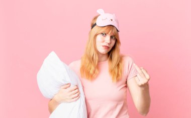 Güzel kızıl saçlı kadın kızgın, sinirli, asi ve agresif hissediyor. Pijama giyiyor ve yastık tutuyor.