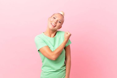 Güzel sarışın kadın kendini mutlu hissediyor ve meydan okumayla yüzleşiyor ya da kutluyor.