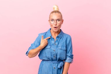 Güzel sarışın kadın şok olmuş ve şaşırmış görünüyor ağzı açık, kendini işaret ediyor.