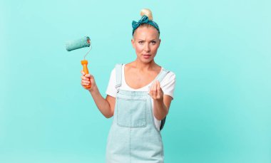 Güzel sarışın kadın kapiş ya da para hareketi yapıyor, sana para ödemeni ve duvar boyamanı söylüyor.