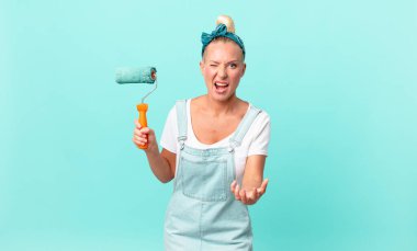 Güzel sarışın kadın kızgın, sinirli, hayal kırıklığına uğramış ve duvar boyuyor.