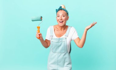 Güzel sarışın kadın mutlu, şaşırmış bir şekilde çözümü ya da fikri fark edip bir duvar boyuyor.