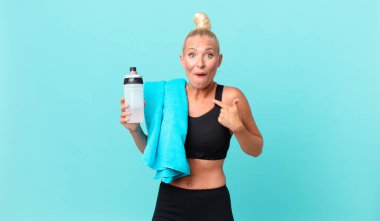 Şok olmuş ve ağzı açık, kendini işaret eden güzel sarışın bir kadın. fitness konsepti