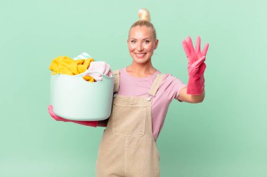 Güzel sarışın kadın gülümsüyor ve arkadaş canlısı görünüyor. Dört numara çamaşır yıkama konseptini gösteriyor.