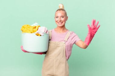 Güzel sarışın kadın gülümsüyor ve arkadaş canlısı görünüyor. Beş numara çamaşır yıkama konseptini gösteriyor.