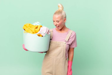 Güzel sarışın kadın agresif bir şekilde bağırıyor, çok kızgın görünüyor çamaşır yıkama konsepti.