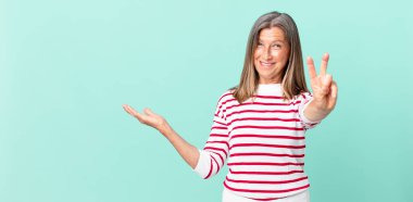 Güzel orta yaşlı bir kadın gülümsüyor ve arkadaş canlısı görünüyor.