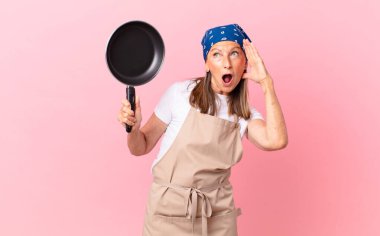 Oldukça orta yaşlı bir kadın mutlu, heyecanlı, şaşırmış ve elinde bir tava tutuyor. Şef konsepti