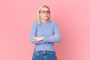 Sarışın, güzel kadın omuz silkiyor, kafası karışık ve kararsız.