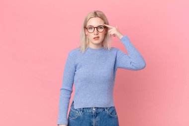 Sarışın, güzel bir kadın. Kafası karışık ve şaşkın. Deli olduğunu gösteriyor.