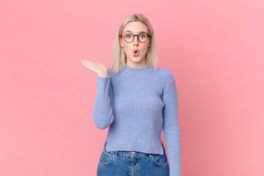 sarışın güzel kadın şaşırmış ve şok olmuş görünüyor, çenesi düşmüş bir nesne tutuyor.