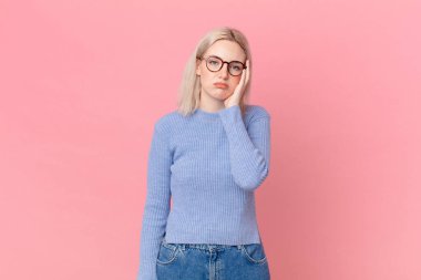 Sarışın, güzel bir kadın. Sıkılmış, hayal kırıklığına uğramış ve uykulu.