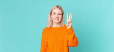 Sarışın, güzel bir kadın gülümsüyor ve arkadaş canlısı görünüyor.