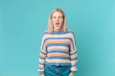 Sarışın, güzel bir kadın agresif bir şekilde bağırıyor, çok kızgın görünüyor.