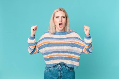 Sarışın, güzel bir kadın kızgın bir ifadeyle agresif bir şekilde bağırıyor.