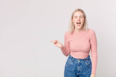 Sarışın, güzel bir kadın agresif bir şekilde bağırıyor, çok kızgın görünüyor.