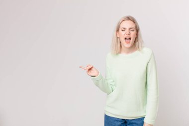 Sarışın, güzel bir kadın agresif bir şekilde bağırıyor, çok kızgın görünüyor.