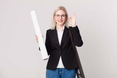 Sarışın, güzel bir kadın kendini mutlu hissediyor, iyi bir jestle onaylıyor. mimar konsepti