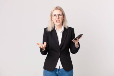 Sarışın, güzel bir kadın kızgın, sinirli ve hayal kırıklığına uğramış görünüyor ve elinde bir cep telefonu var.