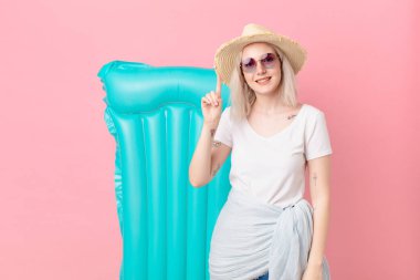 Sarışın, güzel bir kadın gülümsüyor ve arkadaş canlısı görünüyor. Bir numarayı gösteriyor. yaz konsepti