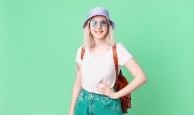 Sarışın, güzel bir kadın mutlu bir şekilde gülümsüyor, eli kalçasında ve kendinden emin. yaz konsepti