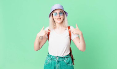 Sarışın, güzel bir kadın mutlu hissediyor ve heyecanla kendini işaret ediyor. yaz konsepti