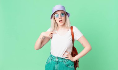 Şok olmuş ve ağzı açık, kendini işaret eden sarışın güzel bir kadın. yaz konsepti