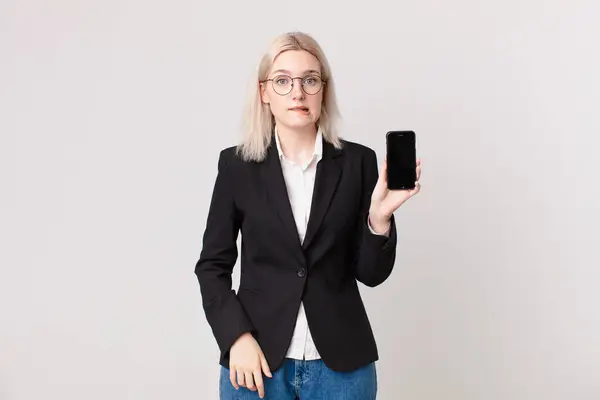 Blond Vacker Kvinna Ser Förbryllad Och Förvirrad Och Håller Mobiltelefon — Stockfoto