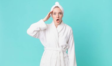 Sarışın, güzel bir kadın. Mutlu, şaşkın, şaşırmış ve bornoz giyiyor.