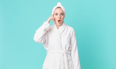 sarışın güzel kadın şaşırmış görünüyor, yeni bir düşünce, fikir ya da konsept fark ediyor ve bornoz giyiyor.