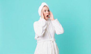 Sarışın, güzel bir kadın mutlu, heyecanlı, şaşırmış ve bornoz giyiyor.