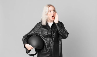 blond pretty woman feeling happy, excited and surprised. motorbike rider concept