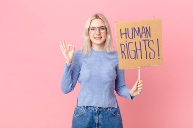 blond woman protesting with a cardboard banner