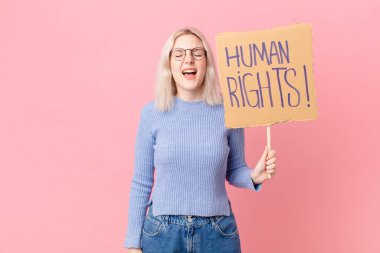 blond woman protesting with a cardboard banner