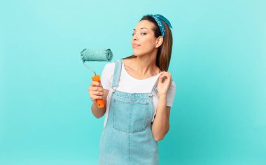 young hispanic woman looking arrogant, successful, positive and proud and painting a wall